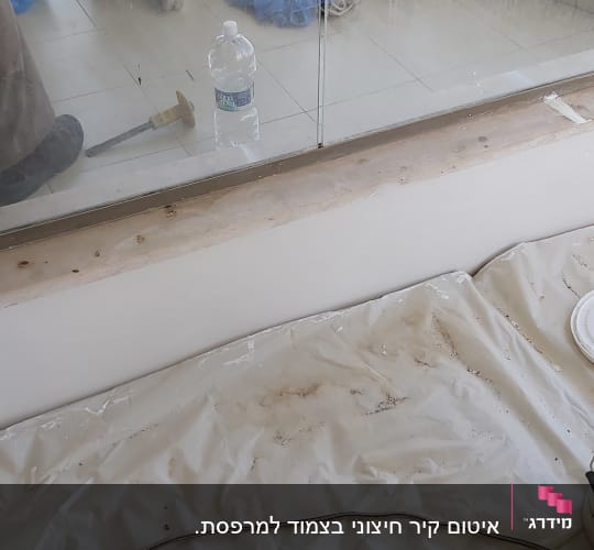 דלי צבע לבן ליד חלון עם מסגרת מתכת